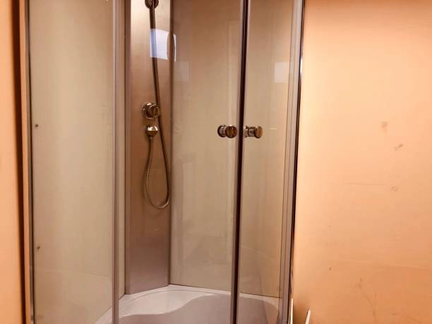 Compact corner shower enclosure with curved glass doors and metal handles. -shower glass panels